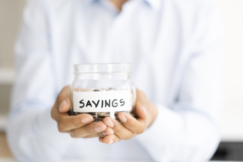 Why Buying a Heat Pump Instead of a Furnace Makes Sense. Photo of someone holding a jar of coins labeled "Savings".