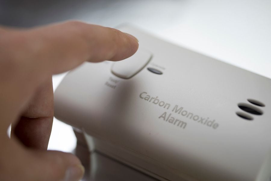 A person presses a carbon monoxide detector. Learn the Facts About Carbon Monoxide.
